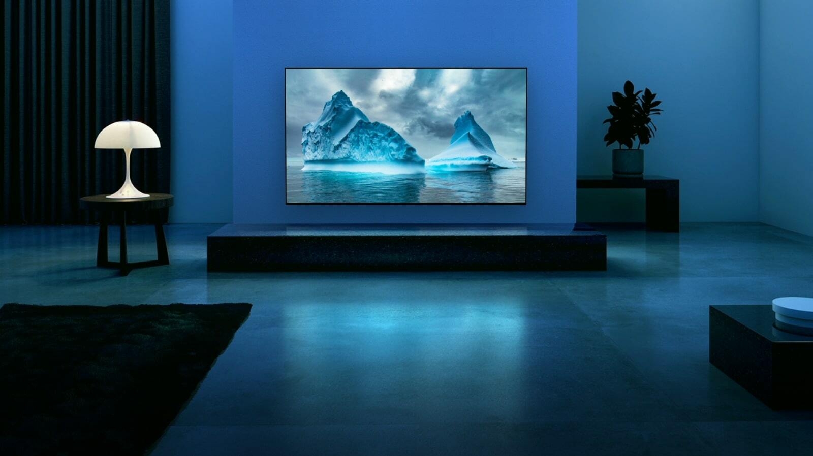 A blue neon circuit moves around on blue glacier image. The camera zooms out and shows this blue glacier within TV screen. The TV is placed in a wide living room with blue background.