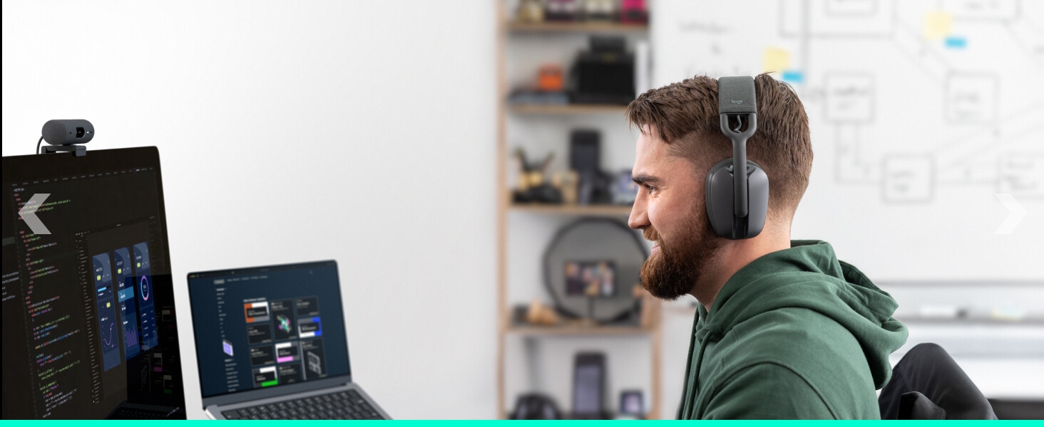 An angle image of a man wearing Zone Vibe 100 and working on a computer