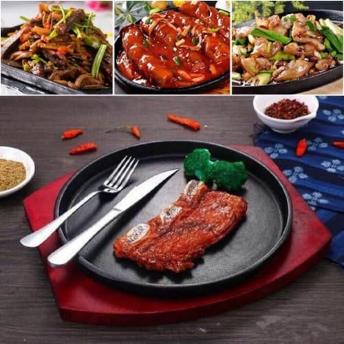 Cast iron hot sizzling plate on wooden tray